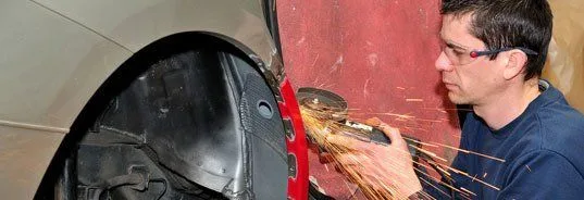 Technician performing collision repair bodywork with an angle grinder